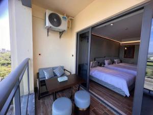 a bedroom with a bed and a desk and a balcony at Zhongzhou International Apartment in Sanya