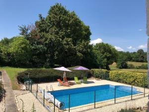 a swimming pool with two chairs and an umbrella at Chez Goret Gites - Gite Skippy Couples only 