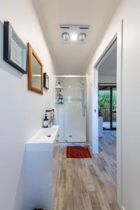 La salle de bains est pourvue d'un lavabo blanc et d'une douche. dans l'établissement Country Nirvana, à Pataua