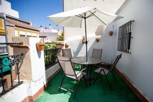 una mesa y sillas en un balcón con sombrilla en Apartamentos Doña Concha en Sevilla