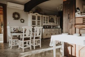 a kitchen with white chairs and a table and cabinets at Dom Malowany - Domki in Wetlina
