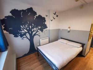 um quarto com um mural de árvore na parede em Kabannas London St Pancras em Londres