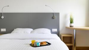 a tray of food on a bed with orange juice at Hotel Cerise Nancy in Nancy