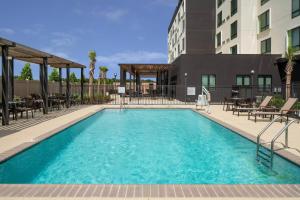 a swimming pool with tables and chairs and a building at Courtyard by Marriott Lafayette South in Lafayette