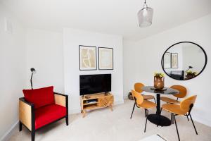 uma sala de estar com uma cadeira vermelha e uma mesa em The Clapham Getaway - Charming 1BDR Flat em Londres