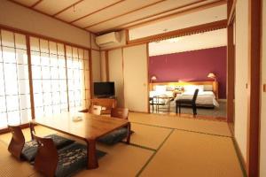 a living room with a table and a bedroom at Sendai Hills Hotel in Sendai
