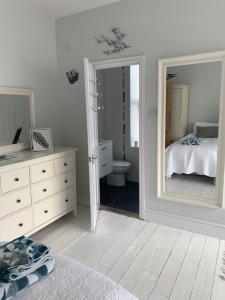 a bedroom with a mirror and a bed and a bathroom at Shoreline in St Ives