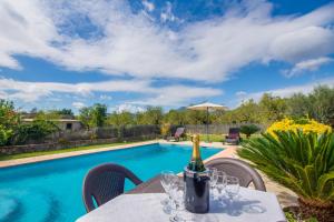 uma garrafa de vinho numa mesa ao lado de uma piscina em Puri em Lloseta