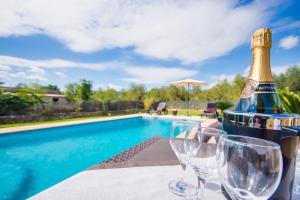 een fles champagne en glazen op een tafel bij een zwembad bij Puri in Lloseta
