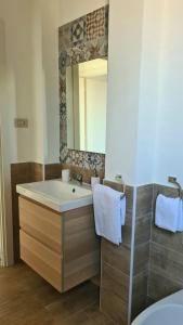 een badkamer met een wastafel en een spiegel bij Àrima Mondello Apartment in Mondello