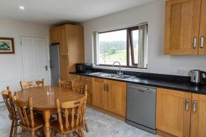 a kitchen with a wooden table with chairs and a sink at Ligford Cottage in Strabane