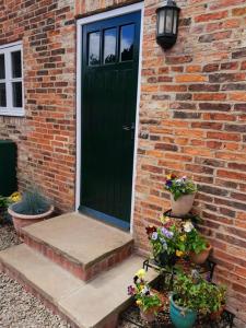 una casa in mattoni con una porta verde e piante in vaso di Vavasour a York