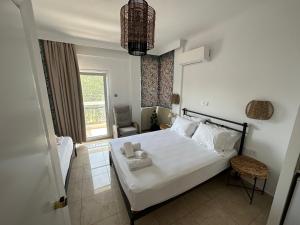 a bedroom with a white bed and a chair at Apartments Villa Effie in Paralia Katerinis