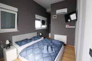 una camera da letto con un letto con cuscini blu e una TV di Rooms Matić a Velika Mlaka