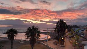 a view of a beach with palm trees and a sunset at Living4malaga Mi Carmela Beach in Málaga