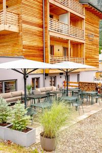 un patio con tavoli e ombrelloni di fronte a un edificio di Apart-Hotel Laurus Lech a Lech am Arlberg