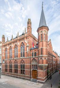 um grande edifício de tijolos vermelhos com uma torre de relógio em Hotel Staatsman em Zwolle