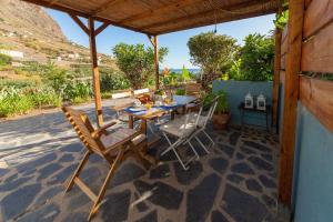 un patio con mesa y sillas bajo un techo en Casa Rural El Arenal en Hermigua