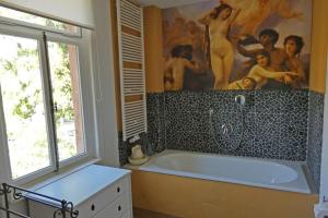 een badkamer met een bad en een groot schilderij aan de muur bij Herrschaftliches Apartment in historischer Villa in Hanau am Main