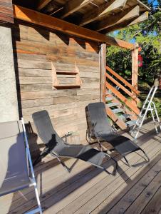 2 sillas y una escalera en una terraza de madera en Chalet Ailleurs Appartement à Molines en Queyras, en Molines-en-Queyras