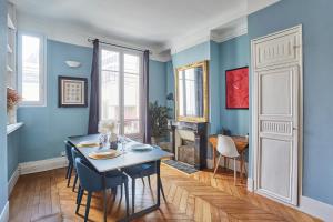 a dining room with blue walls and a table and chairs at Apartment place de l'Etoile By Studio prestige in Paris