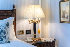 a bed room with a lamp and a plate of food on a table at Powerscourt Hotel, Autograph Collection in Enniskerry