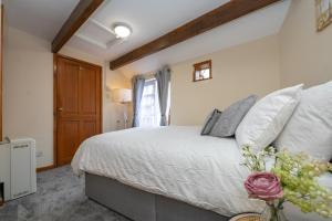a bedroom with a white bed with a vase of flowers at Cosy Cottage in Historic Lincoln in Lincolnshire