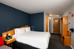 a bedroom with a large white bed and a blue wall at Holiday Inn Express Warwick - Stratford-upon-Avon by IHG in Warwick +32 photos