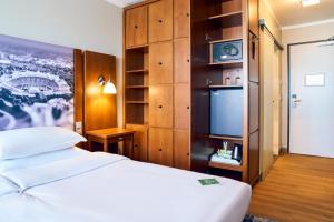 a hotel room with a bed and a flat screen tv at Arthotel Ana im Olympiapark in Munich