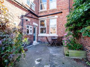 a brick building with a patio with a table and chairs at Pass the Keys Cosy flat close to metro City and hospitals in Gosforth