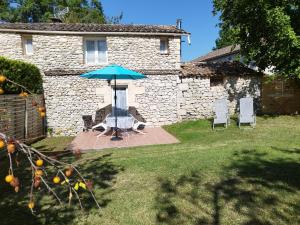 a patio with an umbrella and chairs in a yard at Gite Eynardou in Naussannes +6 photos