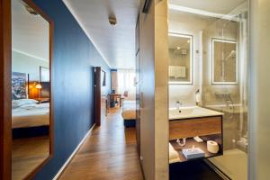 uma casa de banho com um lavatório, uma cama e um espelho. em Arthotel Ana im Olympiapark em Munique