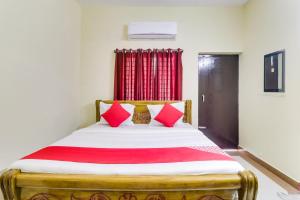 a bed with red pillows in a room at OYO Flagship Hotel Vaiko in Khandagiri