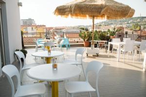 eine Terrasse mit Tischen, Stühlen und einem Sonnenschirm in der Unterkunft Hotel Antagos in Montesilvano