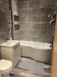 a bathroom with a tub and a toilet and a sink at Contemporary apartment Great Location with private carpark in Keighley
