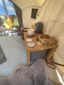 einen Holztisch in einem Zelt mit einem Tisch in der Unterkunft Bell Tents at Llanfair Hall in Llanfairpwllgwyngyll
