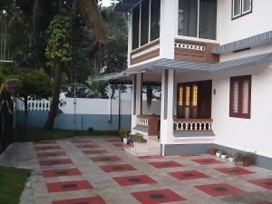 a white house with a courtyard in front of it at NEST Mdy in Mananthavady
