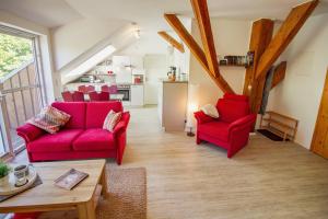 una sala de estar con 2 sillas rojas y una mesa. en Grashaus Leevke, en Krummhörn