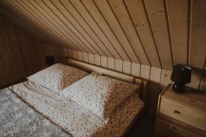 a bed in a room with a wooden wall at Dom Malowany domki in Wetlina