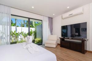 1 dormitorio con 1 cama blanca grande y TV en Escape Villas - Luxury Pool Villa at Anchan Villas, en Ban Phru Champa