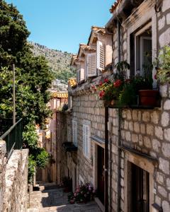 an alley in an old town with flowers on the buildings at Dominus Rooms in Dubrovnik