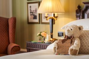 a teddy bear sitting on a bed with a box at Powerscourt Hotel, Autograph Collection in Enniskerry