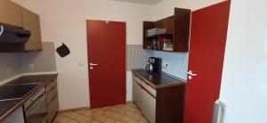 a small kitchen with a red door and a counter at Ferienwohnung Bienenbeute in Ebenweiler