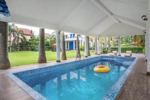 una piscina con una balsa en el medio en Timeless Elegance by StayVista - Poolside Villa with Lawn & Terrace, en Calcuta