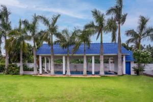 une maison avec des palmiers dans une cour dans l'établissement Timeless Elegance by StayVista - Poolside Villa with Lawn & Terrace, à Kolkata