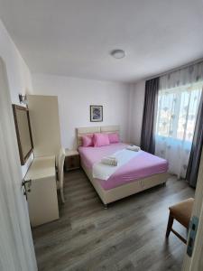 a bedroom with a pink bed and a window at Apartment FLORA in Bregvija