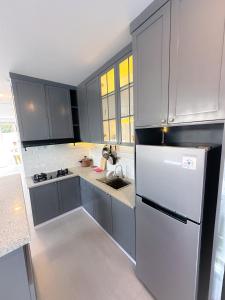 eine Küche mit grauen Schränken und einem Kühlschrank in der Unterkunft Armada Resort Puncak in Sampal 2