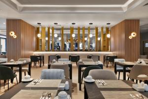 a rendering of a restaurant with tables and chairs at Riu Plaza London Victoria in London