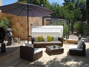 a white couch and two chairs and an umbrella at Au Grand Hôtel de Sarlat - Pavillon de SELVES in Sarlat-la-Canéda