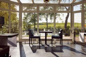 une véranda avec une table et des chaises devant une fenêtre dans l'établissement Van der Valk Golfhotel Serrahn - Adult Only, à Serrahn